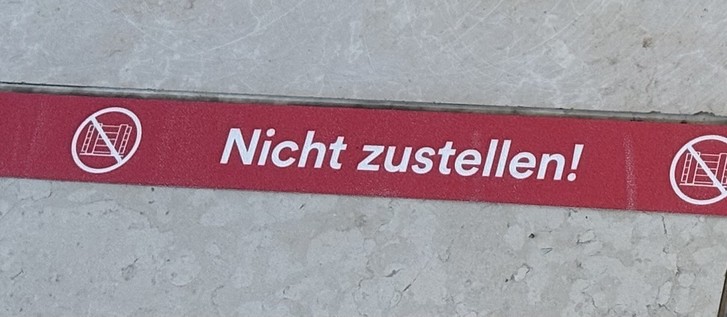Ein rotes Schild mit der Aufschrift „Nicht zusetzen!“ vor einem grauen Hintergrund.